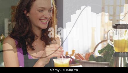 Making woman in purple top dark apron holding clear cup pouring smoothie at counter blender overlay Stock Photo