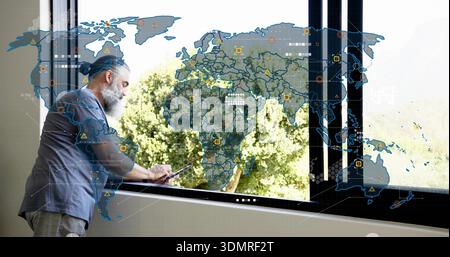 Leaning senior rolled-sleeves using tablet at sill by black window with AR map, trees, copy space Stock Photo