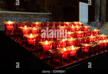 Many burning red votive candles in the dark. Stock Photo