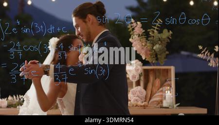 Dancing bride in veil and groom in dark suit holding close at dusk, with blue formulas Stock Photo