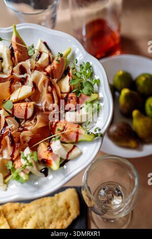 Close up texture of fig and prosciutto salad with balsamic glaze. Appetizing gourmet food background. Stock Photo