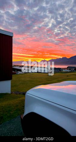 A dramatic sunset illuminates the sky with scattered clouds over ...