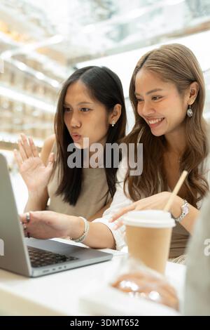 Two young asian women having video call using laptop Stock Photo