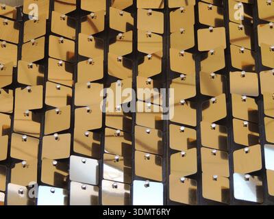 An interior decoration element or design featuring identical golden squares suspended on threads with a sparkling reflective surface Stock Photo