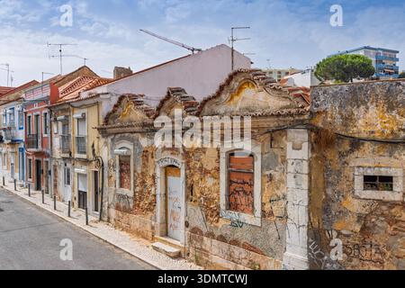 An abandoned, historic building with weathered facade and ornate roofline in Setubal, Portugal, showing signs of decay and urban contrast with modern Stock Photo