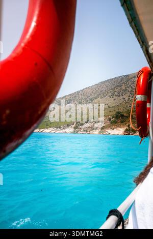 Red lifebuoy on a sailing boat with turquoise water. Ideal for travel brochure, magazine cover, poster. Stock Photo