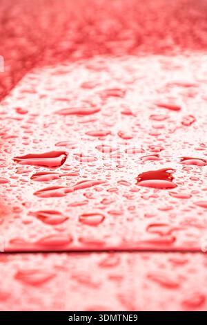 Close-up of red surface with sparkling raindrops, creating texture Stock Photo