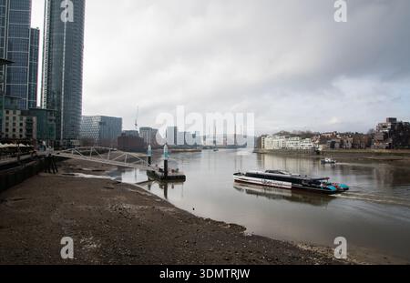 View of the River Thames at low tide from Nine Elms, with Battersea Power Station in the distance under a moody grey sky, London cityscape. Stock Photo