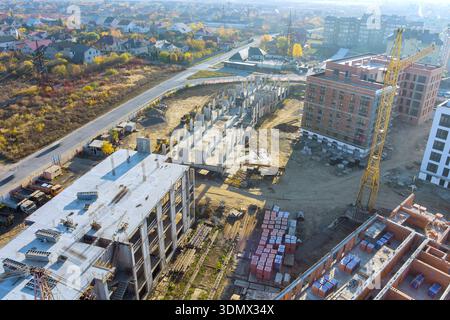 Builders work on constructing new buildings at construction site with using cranes in city Stock Photo