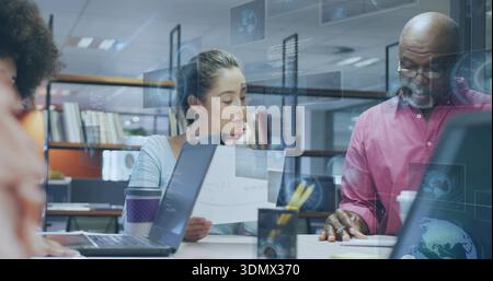 Holding central woman reading printed papers at shared table, with laptops, purple-sleeved cup Stock Photo