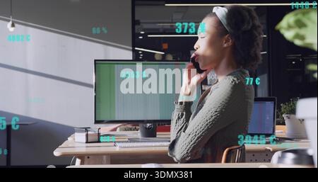 Holding smartphone, green-sweater woman talking while checking spreadsheet at desk, copy space Stock Photo