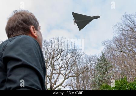 A person observes a reconnaissance drone above tree crowns outdoors Stock Photo