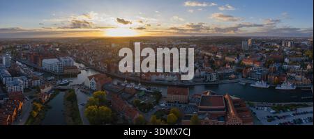 Aerial view of Gdansk at sunset shows Motlawa River, St. Marys Basilica, the medieval Crane, and Hanseatic facades, with warm golden light on red tile Stock Photo
