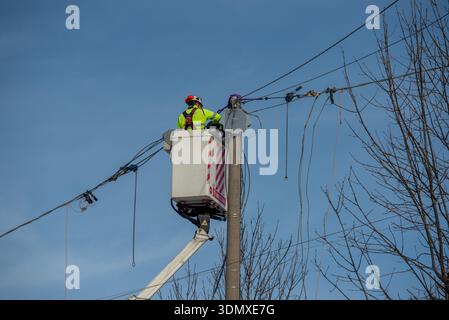 Bergamo, Italy, 27January 2026: Electrical technician performs maintenance on an overhead power line using a lifting platform. He works at height on e Stock Photo