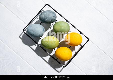 Easter eggs drying on a cooling rack after being naturally dyed with hibiscus and turmeric, creating a beautiful display of yellow and green hues, rea Stock Photo