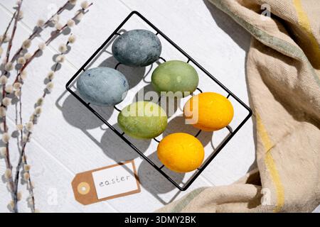 Easter eggs drying on a cooling rack after being naturally dyed with hibiscus and turmeric, creating a beautiful display of yellow and green hues, rea Stock Photo
