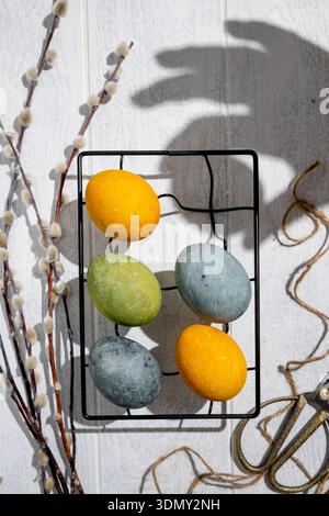 Easter eggs drying on a cooling rack after being naturally dyed with hibiscus and turmeric, creating a beautiful display of yellow and green hues, rea Stock Photo