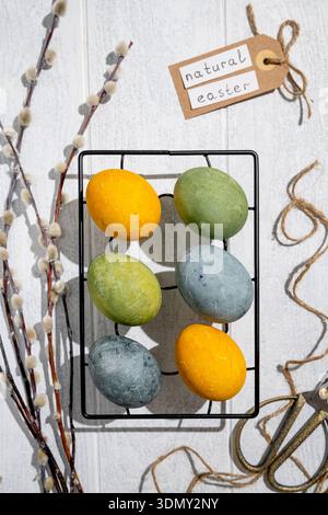 Easter eggs drying on a cooling rack after being naturally dyed with hibiscus and turmeric, creating a beautiful display of yellow and green hues, rea Stock Photo