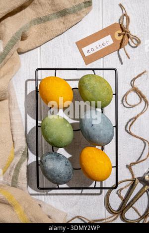 Easter eggs drying on a cooling rack after being naturally dyed with hibiscus and turmeric, creating a beautiful display of yellow and green hues, rea Stock Photo