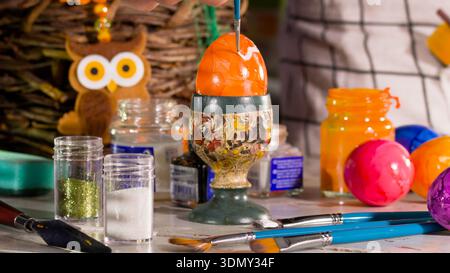 People are painting colorful eggs during a spring festival in a workshop setting with art supplies and decorations Stock Photo