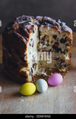 Easter kulich cake with raisins and painted eggs on a table. Easter still life. Orthodox Eater celebration. Colourful eggs with Easter panettone cake Stock Photo