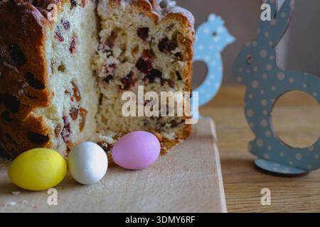 Easter kulich cake with raisins and painted eggs on a table. Easter still life. Orthodox Eater celebration. Colourful eggs with Easter panettone cake Stock Photo