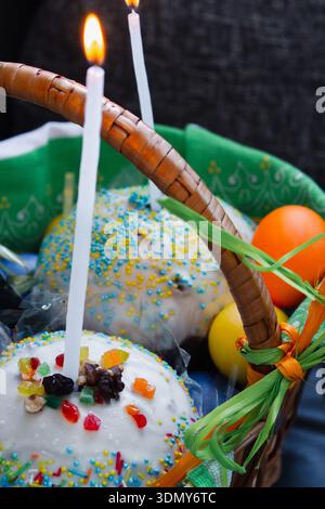 Easter cake with painted eggs and candles in a basket. Easter still life. Orthodox Eater celebration. Colourful Easter eggs with sweet cake in basket Stock Photo