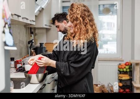 A couple enjoys a morning routine together, preparing breakfast in their cozy kitchen. The warm atmosphere and diverse fresh ingredients set the perfe Stock Photo