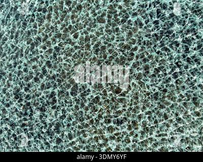 Detailed close-up of shattered and cracked tempered glass, showcasing intricate patterns in the broken surface. The texture captures the complexity an Stock Photo