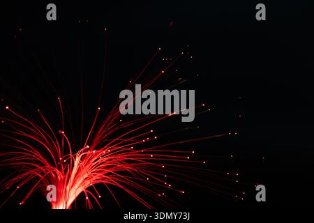 Vibrant red neon lights create a dazzling effect against a dark background with subtle smudging, forming an abstract pattern reminiscent of lively cit Stock Photo