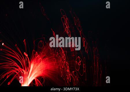 Abstract neon light trails create vibrant red patterns against a dark background. The glowing lines form unique shapes and smudges, adding a modern ar Stock Photo