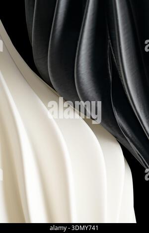 Abstract close-up of black and white plastic waves creating a textured pattern. The smooth materials form undulating curves, providing an elegant and Stock Photo