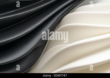 An abstract composition featuring smooth, flowing waves in black and white plastic. The elegant curves create a modern and minimalist background, idea Stock Photo