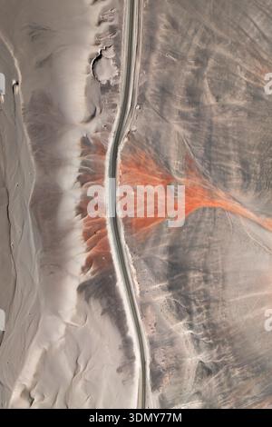 Aerial view of a winding road cutting through a dense green forest and ...