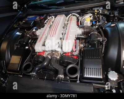 High-performance automotive engine featuring dual overhead camshafts and various intricate components inside a well-lit engine bay Stock Photo