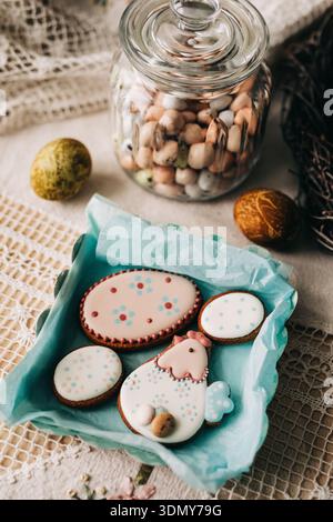 A delightful display of festive easter cookies decorated with pastel icing, nestled in a blue paper-lined basket, surrounded by decorative eggs and a Stock Photo
