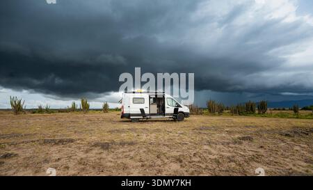 A motorhome parked in the expansive Tatacoa Desert, Colombia. The stormy sky looms overhead, creating a dramatic scene perfect for digital nomads and Stock Photo