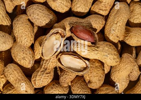 A detailed close-up image of whole peanuts in their natural, textured shells. The arrangement highlights the earthy tones and intricate patterns found Stock Photo