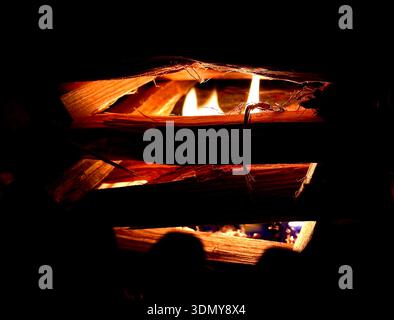 A close-up shot of a crackling fire surrounded by wooden logs, providing warmth and coziness on a cold winter night, creating an inviting and peaceful Stock Photo