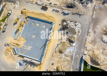 Workers are setting up foundation for new building at construction site with various machinery, equipment. Stock Photo