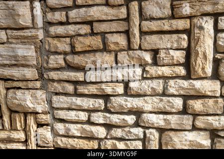 Background texture of a wall made of rough light colored rectangular stones. Stock Photo