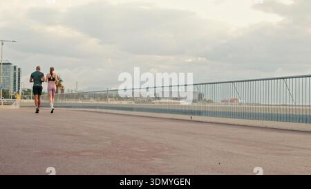 Multi-ethnic couple training together in summer on the seafront. Street work out concept, couple goals and motivation, Back view Stock Photo
