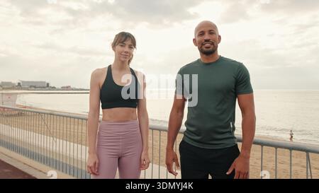 A calm confident pair of athletes standing on the embankment and looking at camera Stock Photo