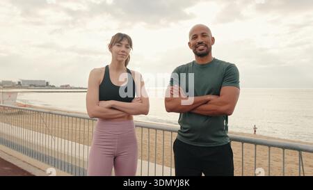 A calm confident pair of athletes standing on the embankment and looking at camera, the emotion of confidence and victory, to achieve and not give up. Stock Photo