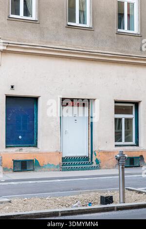A pale doorway sits within a weathered exterior, topped by a red neon sign reading 'Girls Girls.' The worn walls, chipped paint, and teal steps create Stock Photo