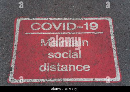 Faded COVID-19 "Maintain social distance" pavement sign on street in Cambridge.Cambridge,England Stock Photo