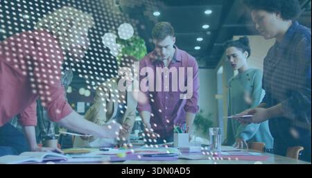 Leaning team of six wearing blazer, rolled sleeves reviewing documents on meeting table with tablet Stock Photo