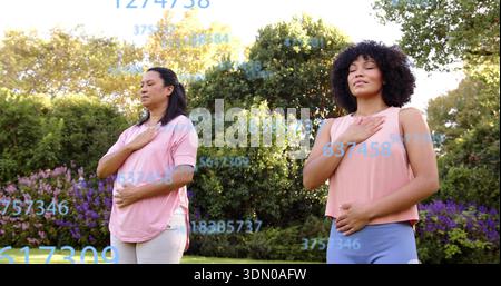 Practicing two women breathing in garden, wearing pink tops near purple shrubs, blue overlays Stock Photo