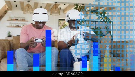 Sitting two men wearing VR headsets, holding controllers on tan sofa in living room, blue overlay Stock Photo
