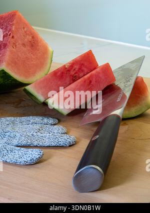 Still life of a wooden cutting board with a Japanese cleave, watermelon and a cut-resistant glove, 2026, USA Stock Photo